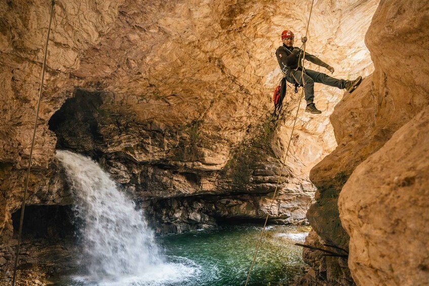A person rappelling down a rocky cliff into a waterfall. 3
