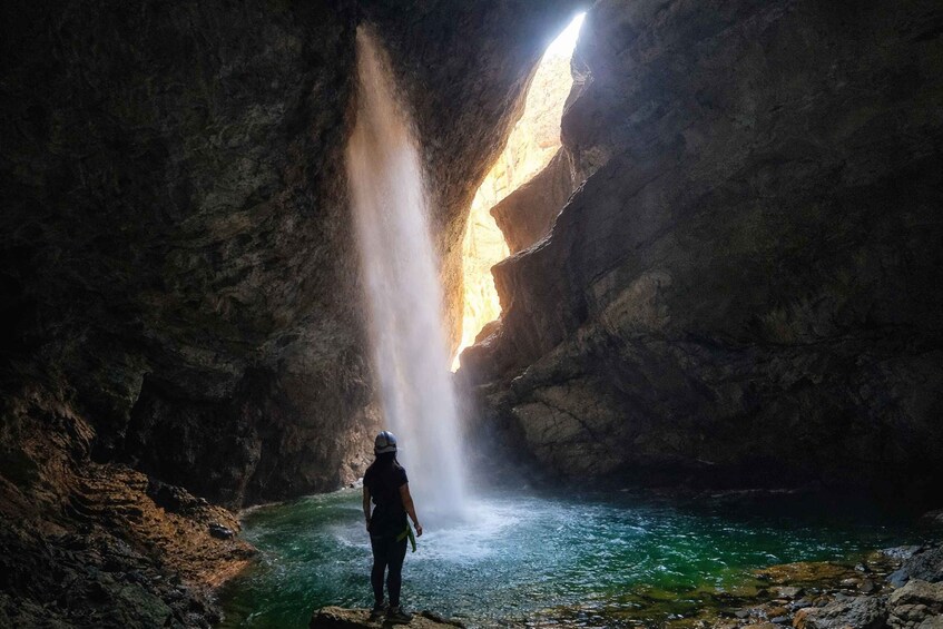 A person standing by a waterfall inside a cave. 4