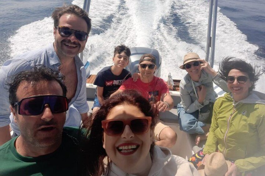 A group of people on a boat with water splashing behind them. 5