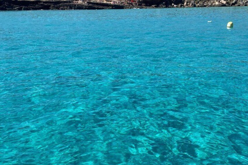 Clear turquoise water, a rocky shoreline, and a buoy. 4
