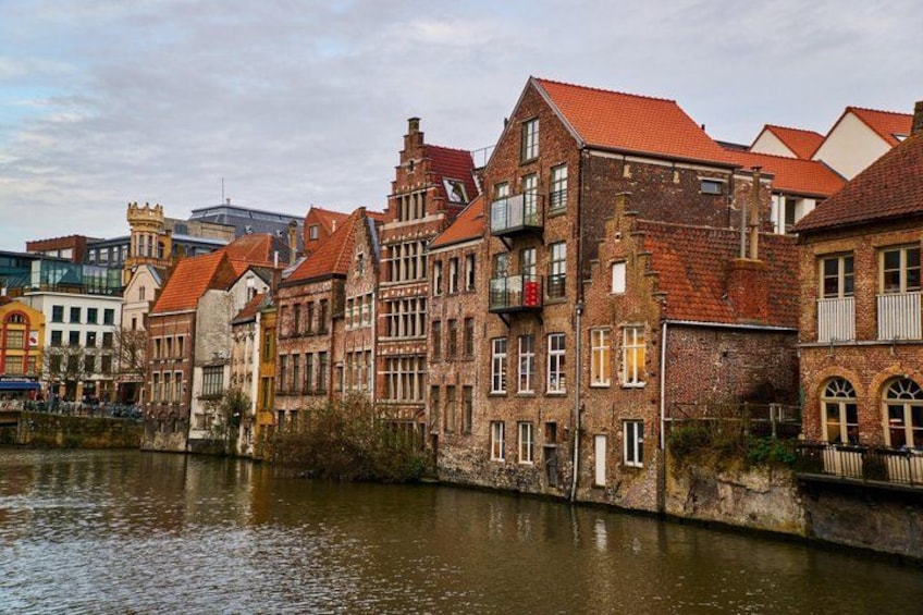 A river with buildings along the bank, featuring red-tiled roofs and a mix of architectural styles. 2
