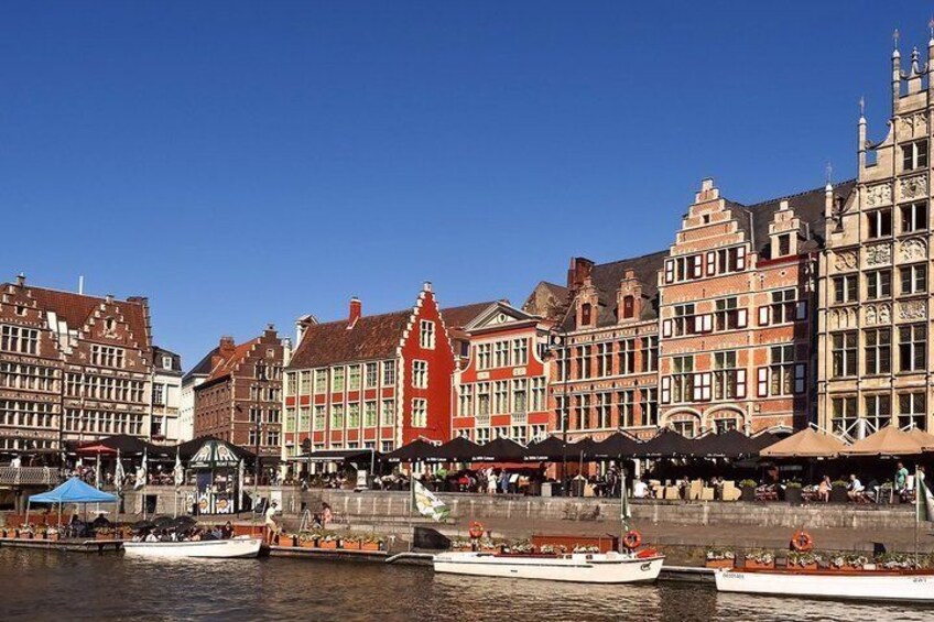 A riverside with historic buildings, boats, and a pedestrian walkway. 3