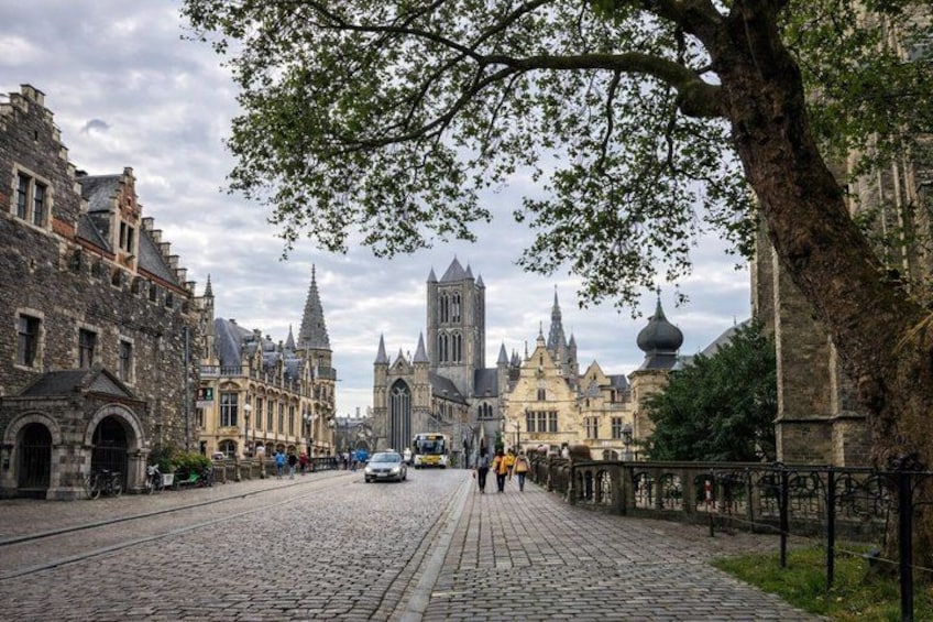 A cobblestone street lined with historic buildings, including a church with a spire. 5