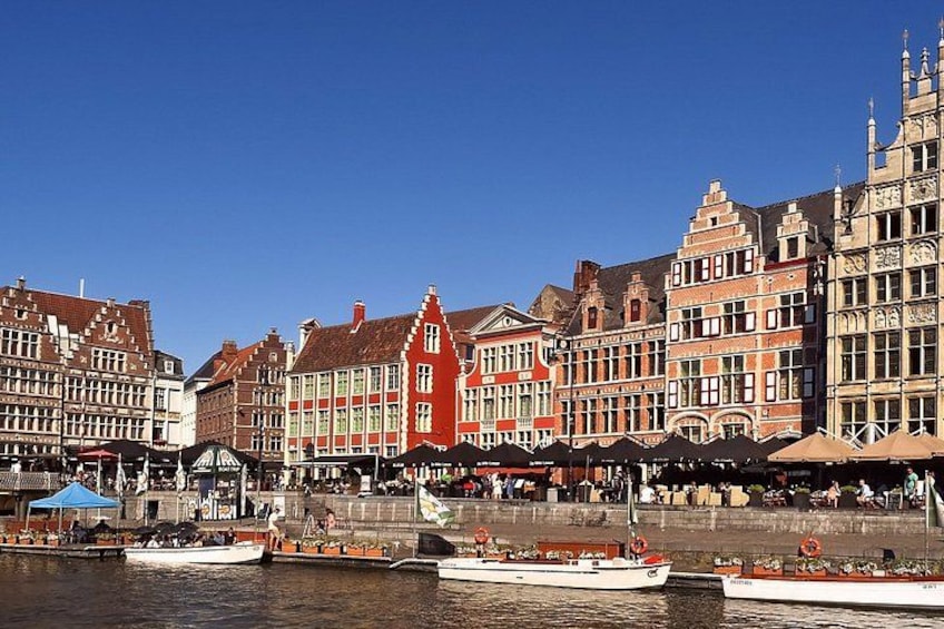 A riverside town with historic buildings, boats, and a clear blue sky. 3