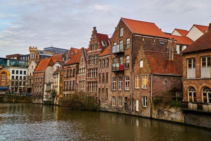 A river with buildings along the bank, featuring red-tiled roofs and a mix of architectural styles. 2