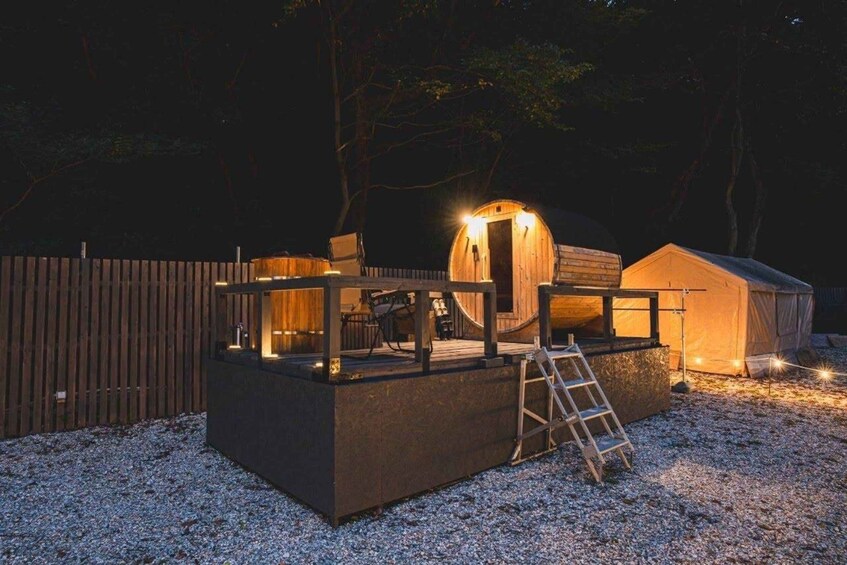 A wooden structure with a ladder, a wooden fence, and a tent-like building at night. 2