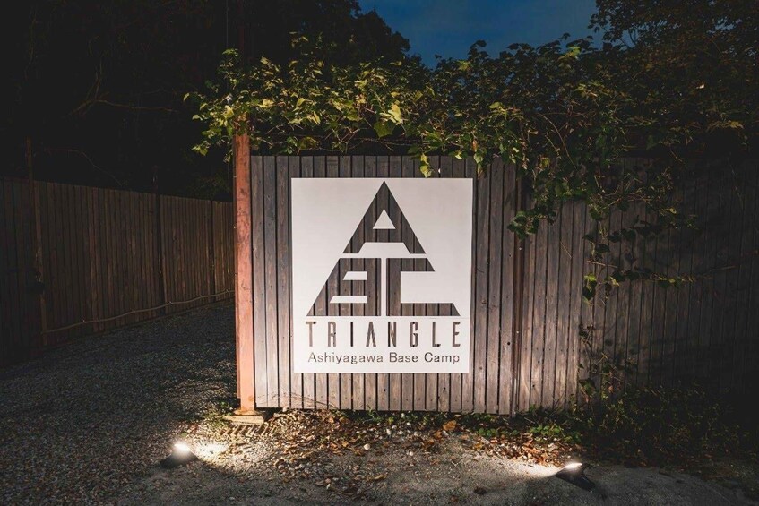 A sign for Ashiyagawa Base Camp with a triangular logo. 1