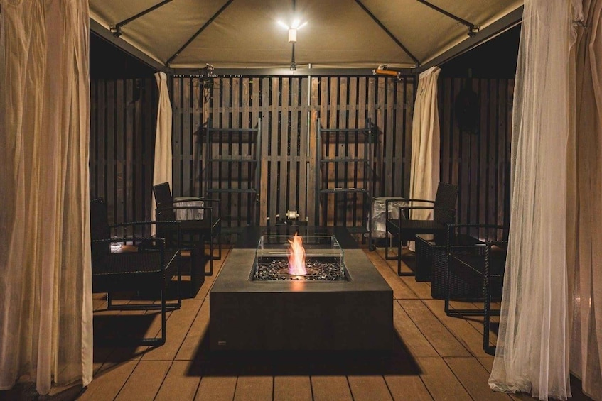 An outdoor patio with a fire feature, chairs, and a covered area. 5