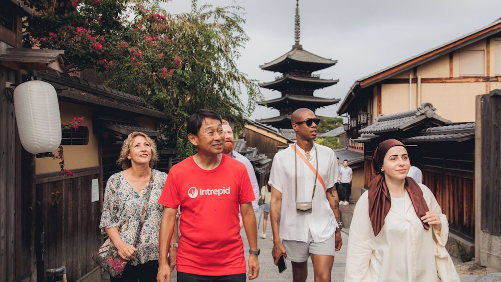 A group of people walking past traditional Japanese architecture, including a pagoda. 1