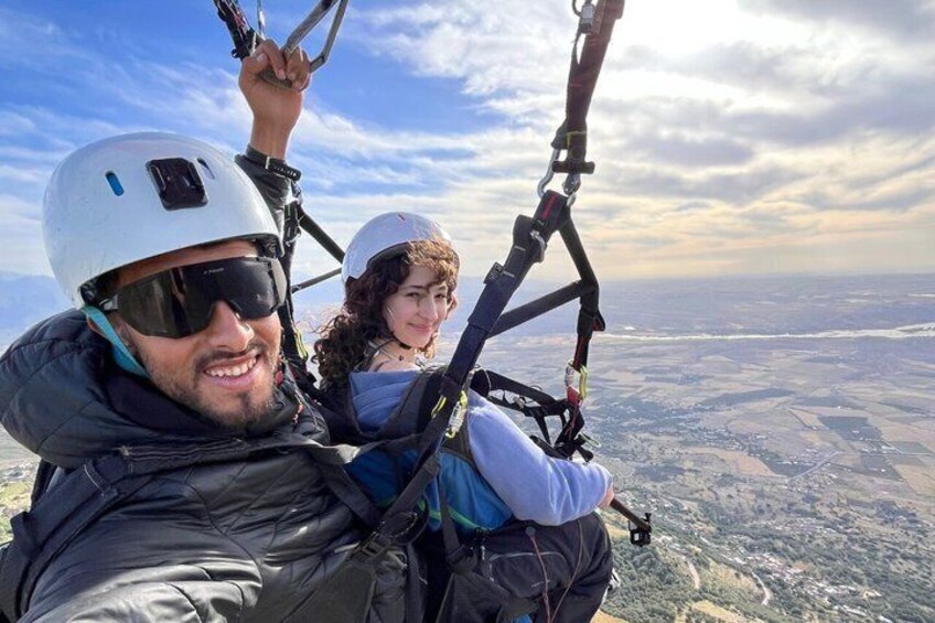 Two people on a tandem paragliding flight with a landscape view. 3