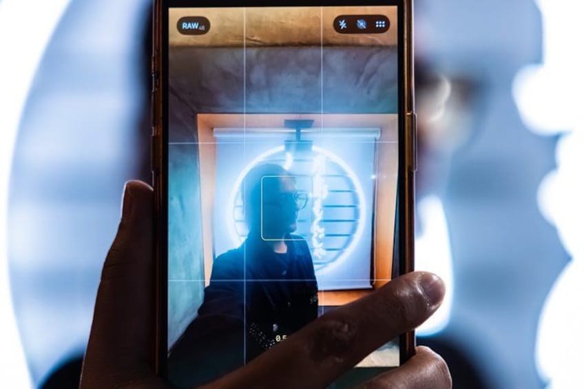 A hand holding a smartphone with a photo editing app open, displaying a photo of a person with a circular object in the background. 3
