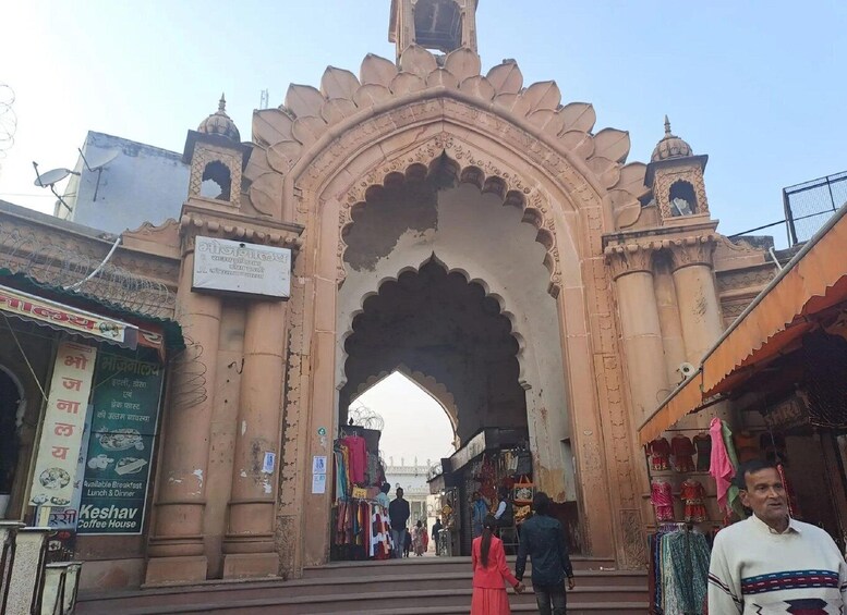 An ornate archway with shops and people around it. 3