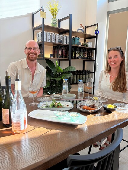 A dining table with wine bottles, glasses, and plates of food. 2