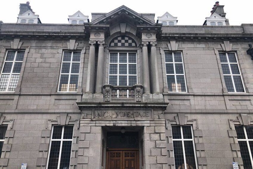 A large stone building with a central entrance, flanked by columns and a decorative pediment. 4