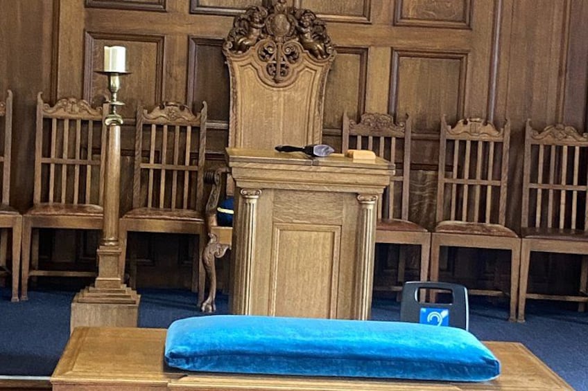 A wooden altar with a blue cloth, a candle, and a chair. 3