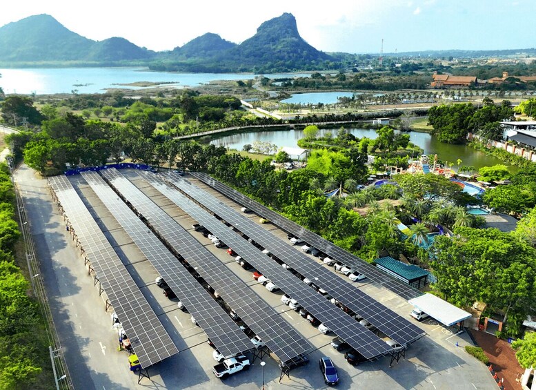 A solar farm with rows of panels, a parking area, and a mountainous landscape in the background. 2