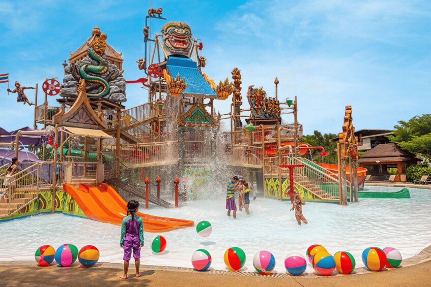 A water park with a large slide, water play area, and colorful beach balls. 5