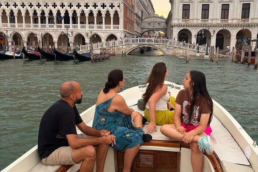 A group of people on a boat in a canal with historic buildings in the background. 2