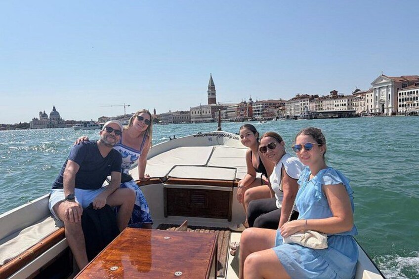 A group of people on a boat with the Grand Canal and the Doge's Palace in Venice in the background. 1