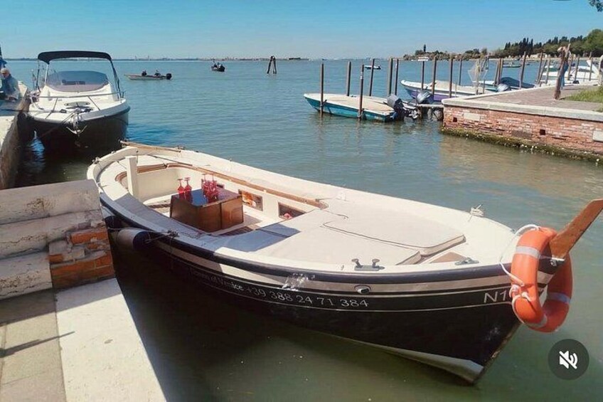 A small boat docked at a pier with other boats in the background. 4