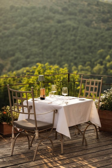 A table set for two with a view of a forested hillside. 1