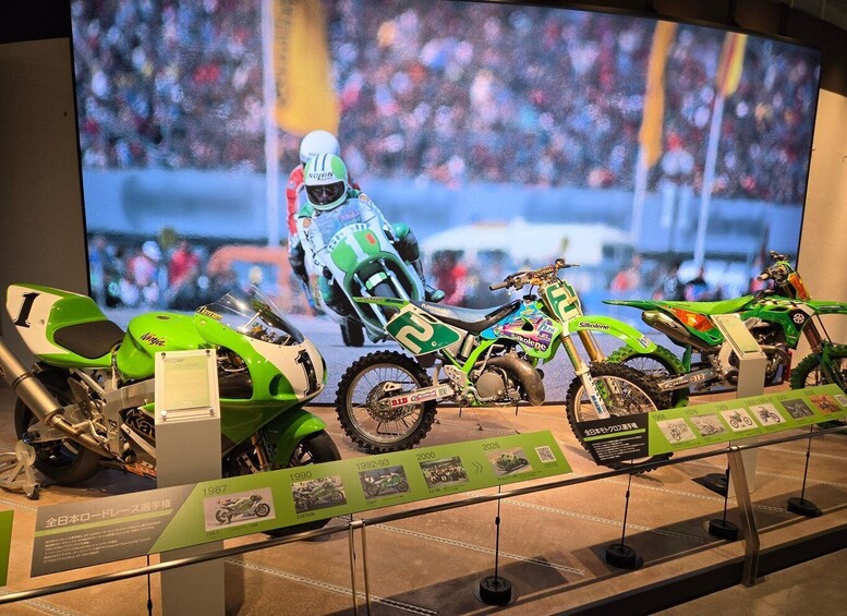 A motorcycle exhibition with models from 1987 to 2026, including a racing bike and a green dirt bike. 3