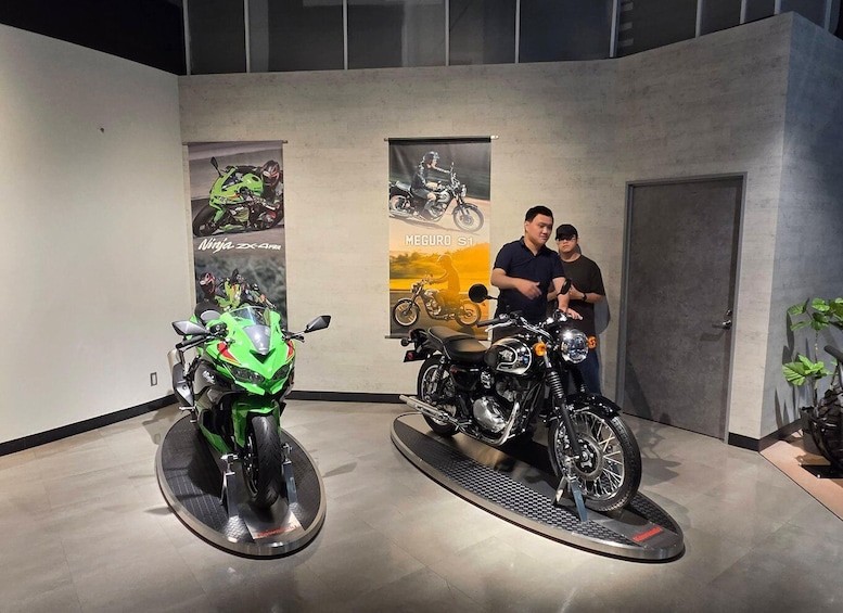 Two motorcycles on display stands in an indoor setting with posters on the walls. 2
