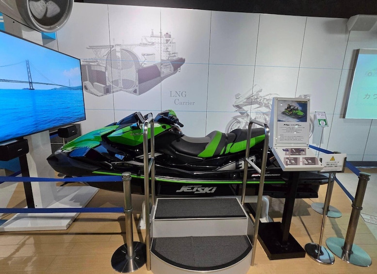 A green and black jet ski on display with a monitor and a sign in the background. 5