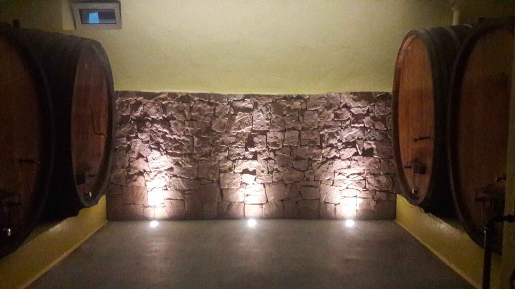 A stone wall with two wooden barrels on either side. 2