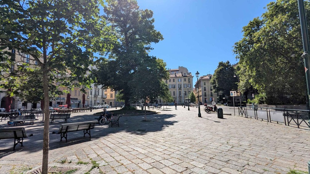 A paved square with benches, trees, and buildings in the background. 4