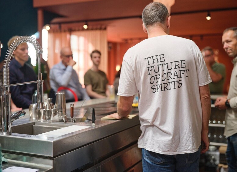 A person standing at a bar with a white t-shirt reading 'THE FUTURE OF CRAPT SPIRITS'. 2