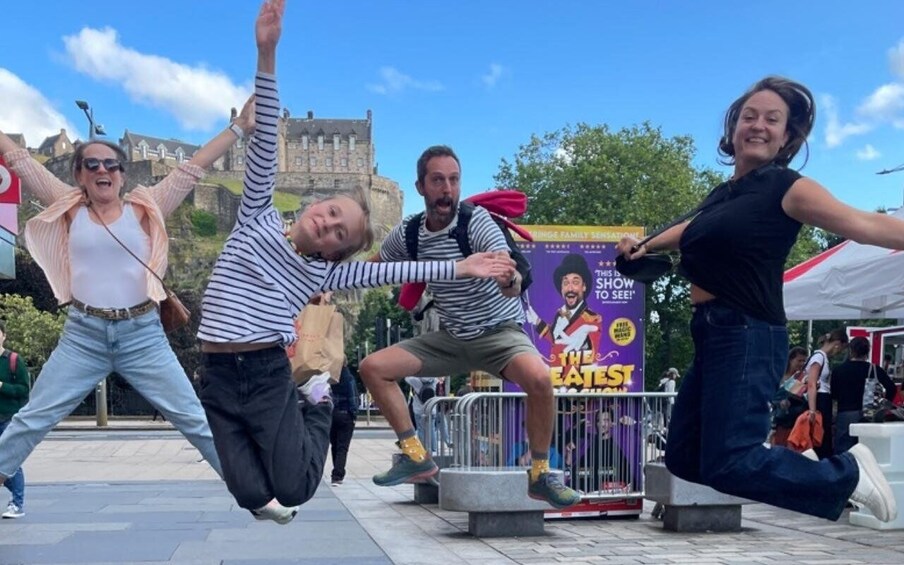 A group of people jumping in an outdoor area with a castle in the background. 5