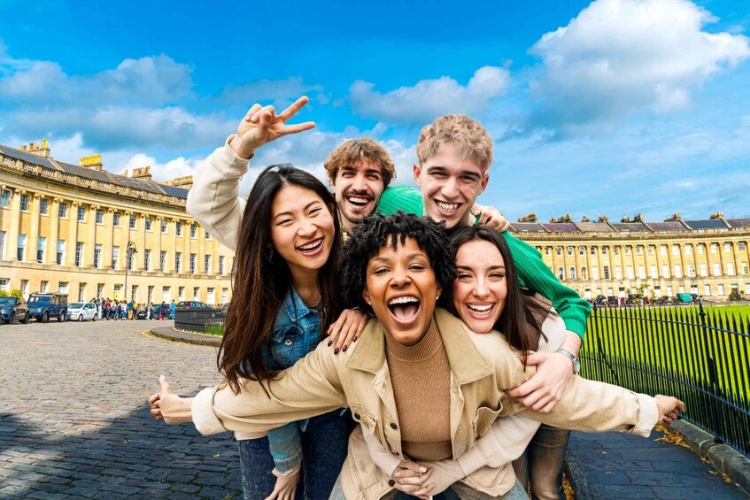 A group of people posing in front of a historic building with a clear blue sky. 4