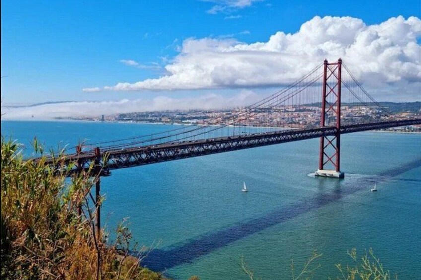 A red bridge spanning a body of water with a cityscape in the background. 2