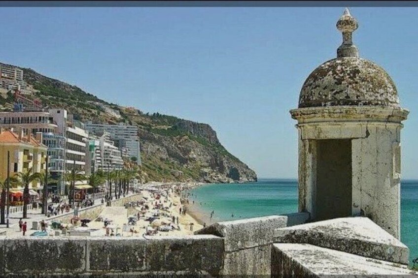 A coastal town with a beach, a stone structure, and buildings along the shore. 5