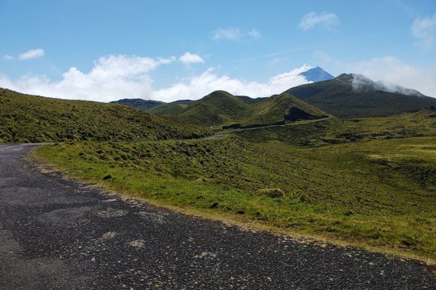 A winding road through a green landscape with hills and a mountain in the background. 3