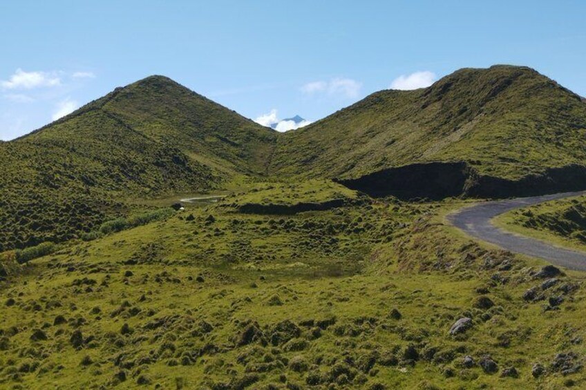 A winding road through a green, hilly landscape with two prominent hills. 1
