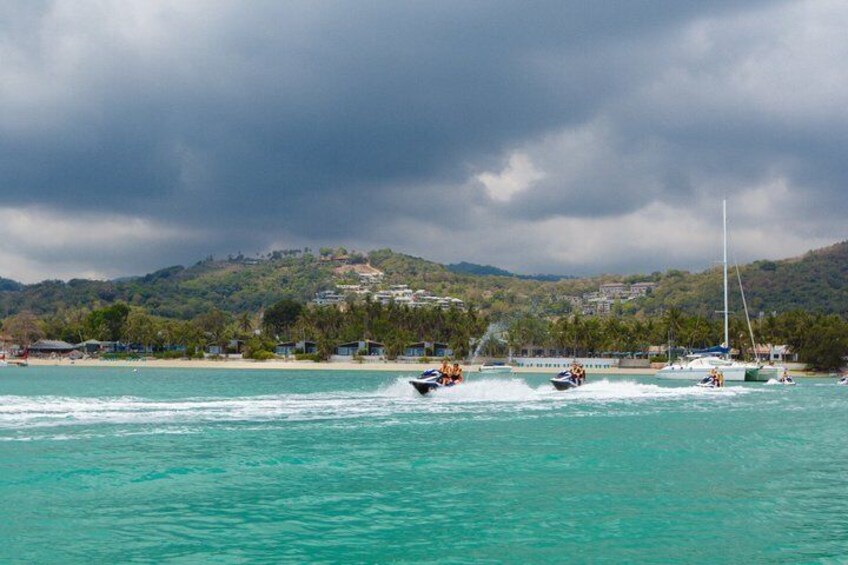 A coastal area with boats, a sailboat, and a mountainous landscape in the background. 3