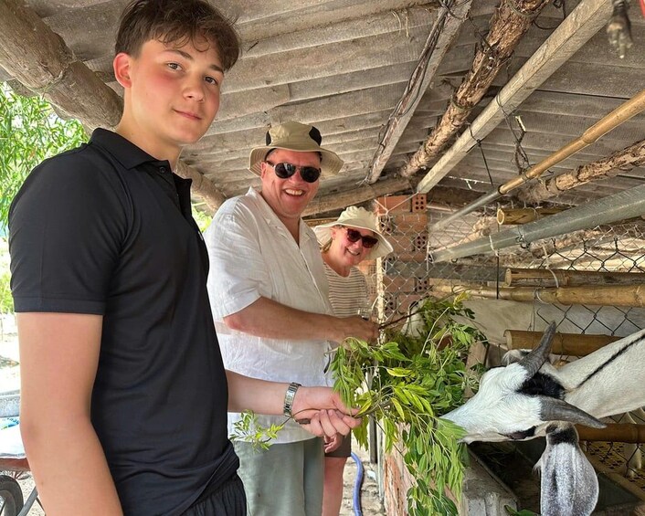 A person holding a plant, another person in the background, and a bird in a cage. 2