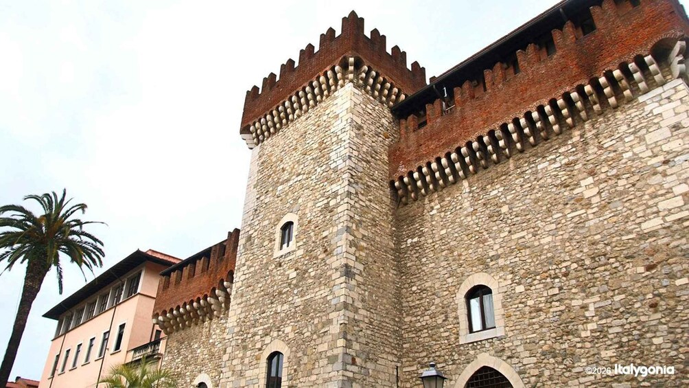 A historic stone castle with crenellated battlements and arched windows. 1