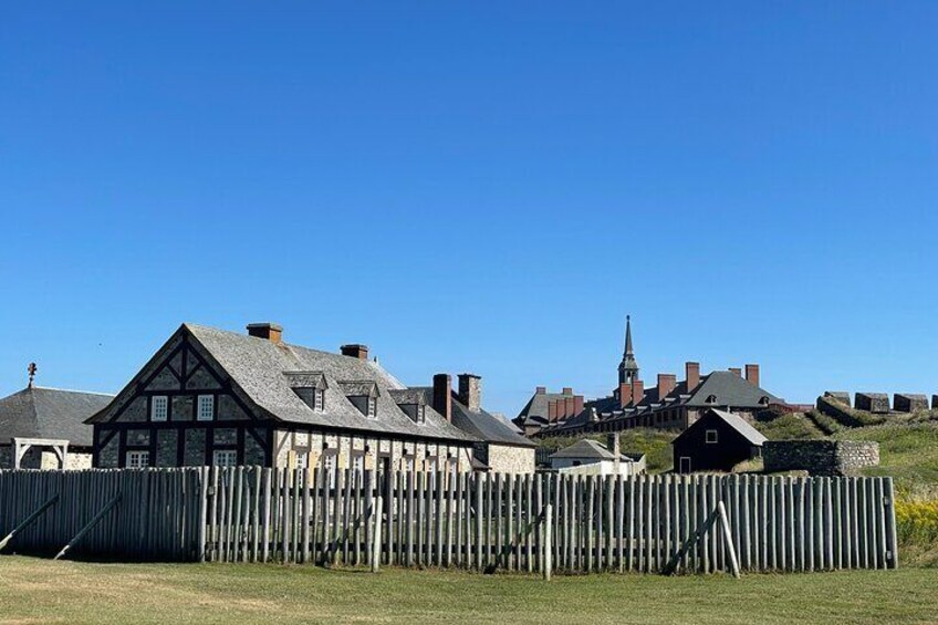 A traditional half-timbered house with a steep roof, a church steeple, and a wooden fence. 2