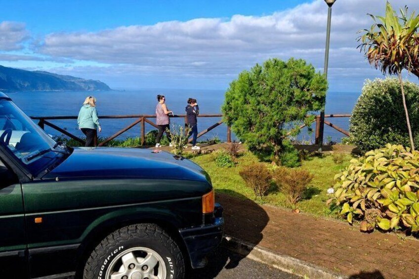 A parked car, a wooden fence, and a view of the ocean. 3