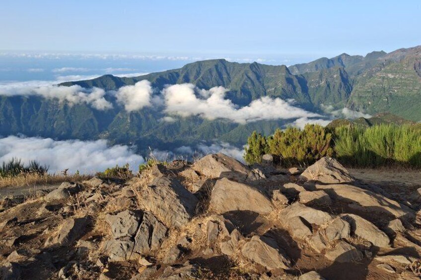 A mountainous landscape with rocky terrain and a view of cloud-covered valleys. 5