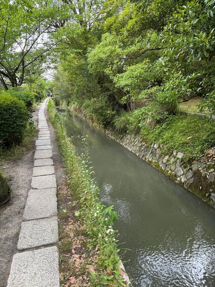 A narrow waterway flanked by stone steps and lush greenery. 4