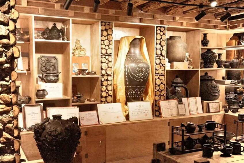 A museum display with wooden shelves, pottery, and a mannequin. 2