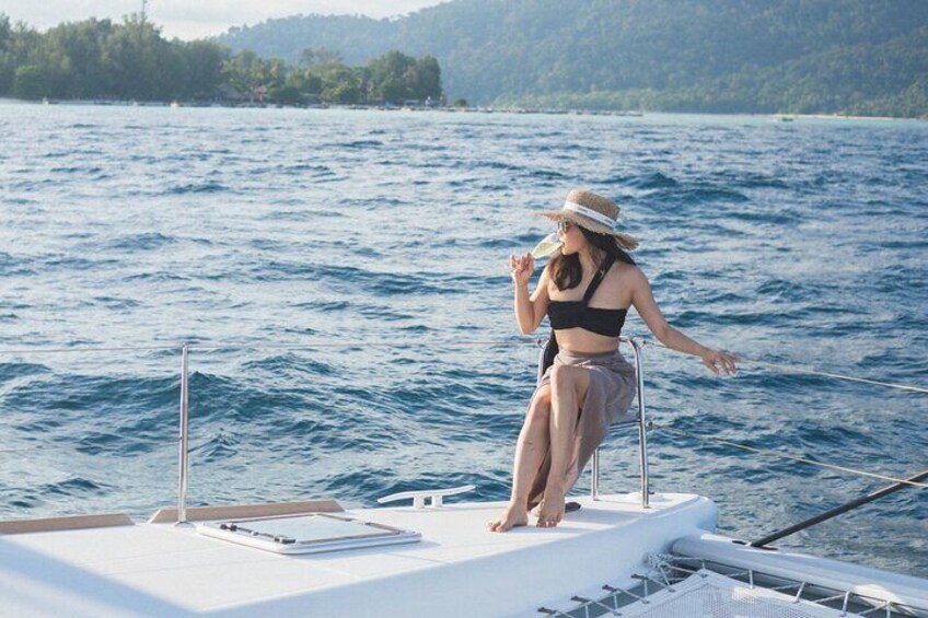 A person standing on a boat's deck, facing a large body of water with a distant shoreline. 4