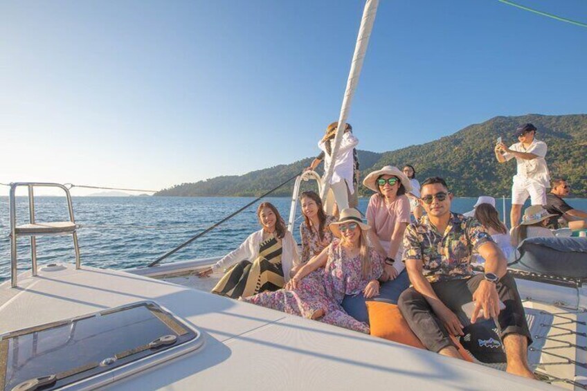 A group of people on a boat with a clear view of the water and a hilly landscape in the background. 3