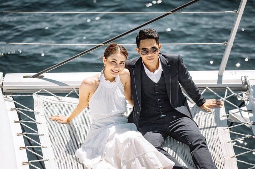 A couple on a boat with a clear view of the water and a metal railing. 2