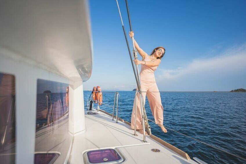 A person on a boat, holding onto a pole, with water and a distant landmass in the background. 5