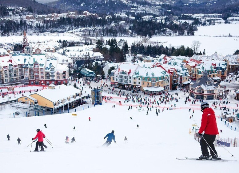 A snowy ski resort with skiers, colorful buildings, and a town in the background. 1